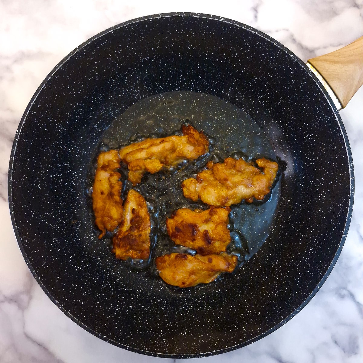 Step 5 - Chicken bites frying in shallow oil in a pan.
