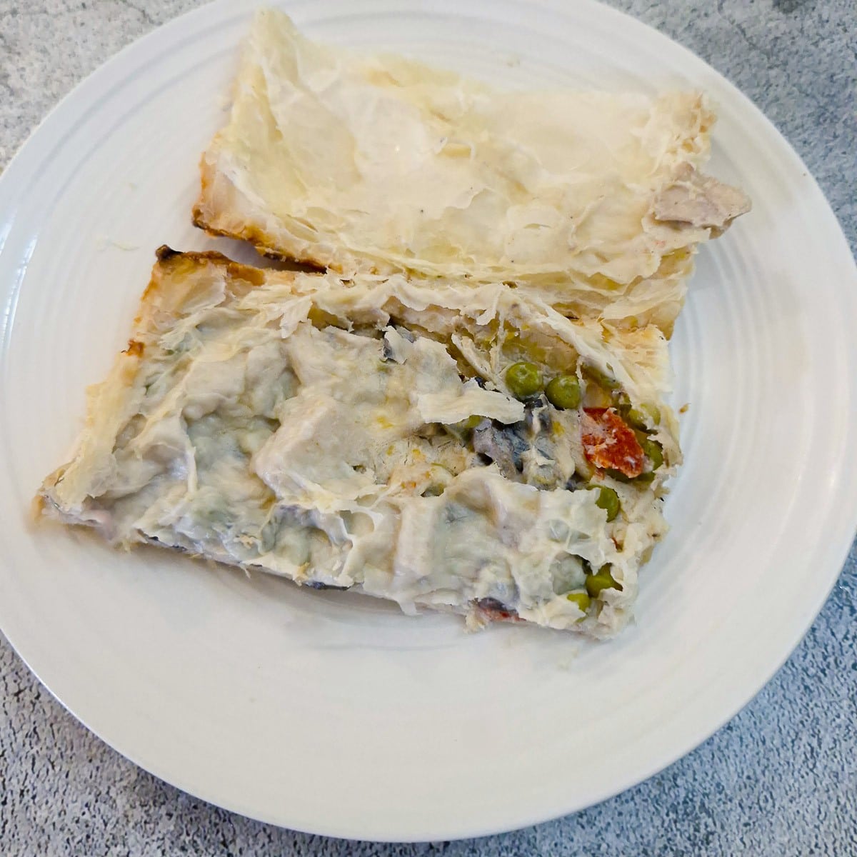 Half a pie with the pastry lid peeled back to show the creamy filling inside.