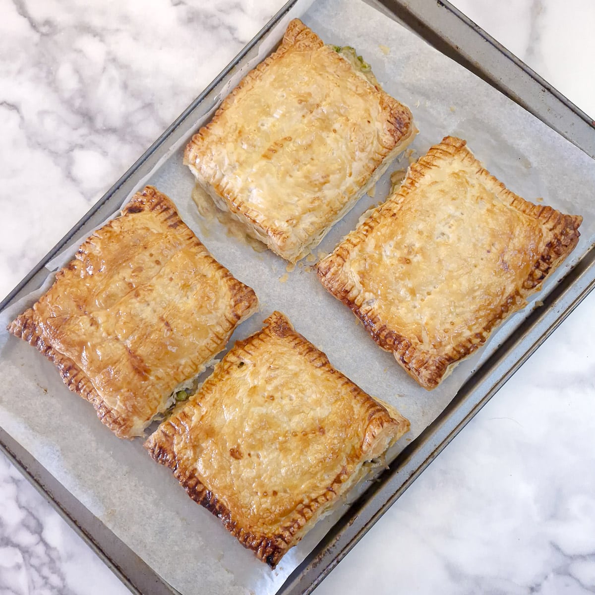 4 baked puff pastry chicken a la king pies on a baking sheet.