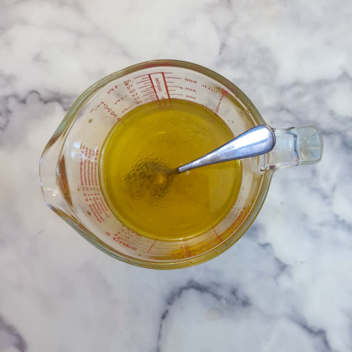 A glass jug holding an oil and vinegar marinade.