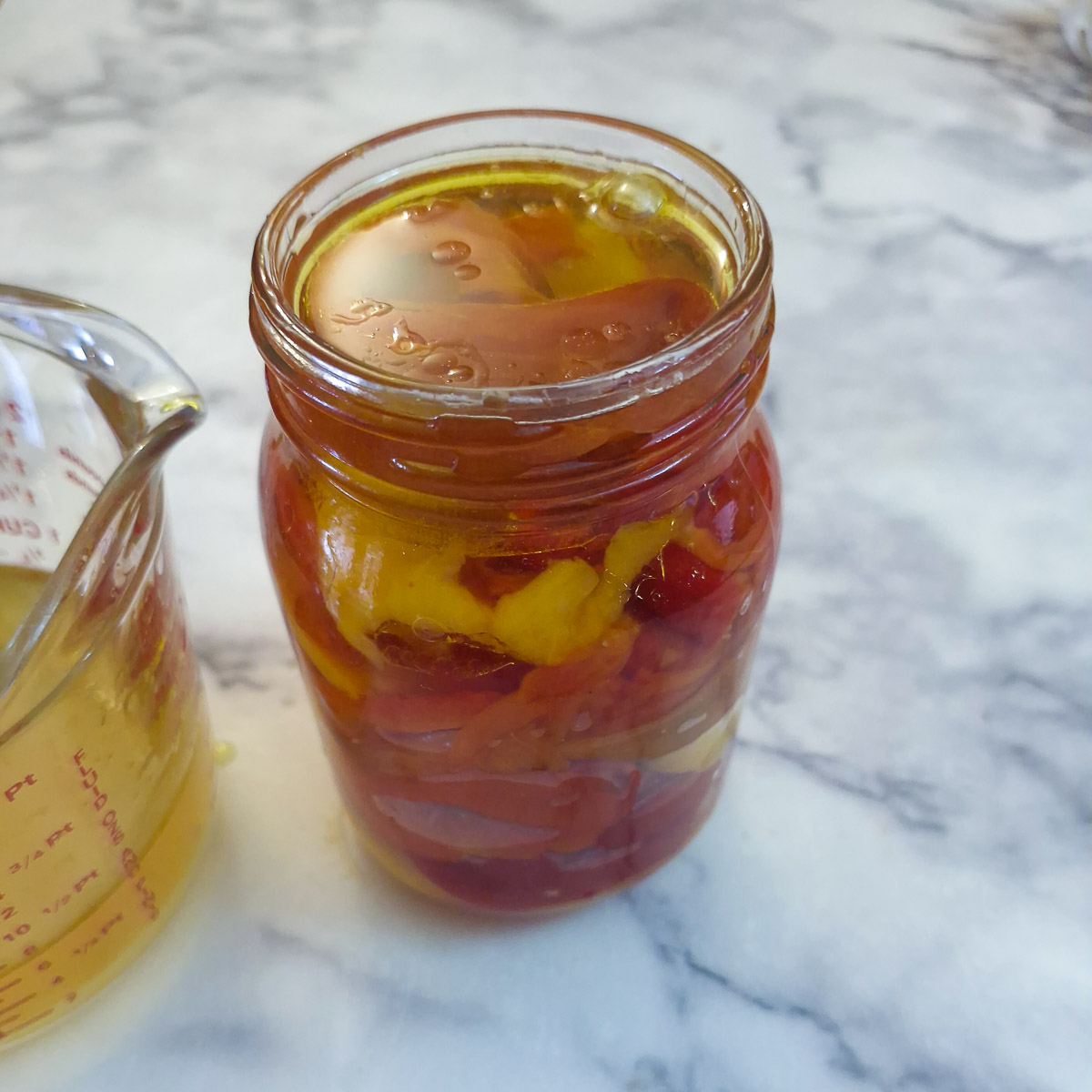 A jar of ref peppers with the marinade poured over.