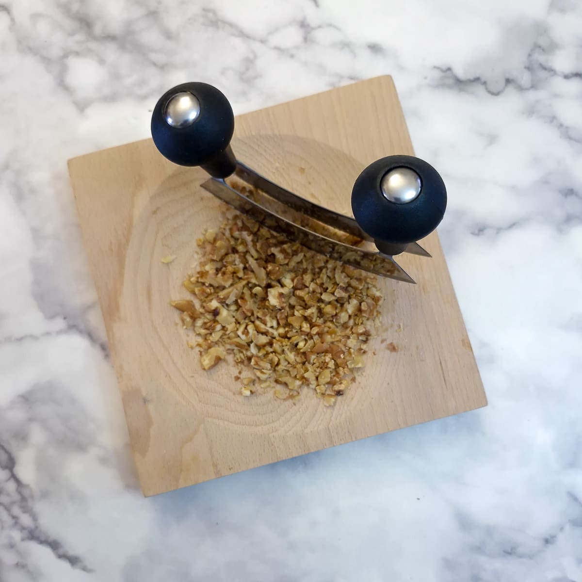 Walnuts being chopped with a herb cutter.