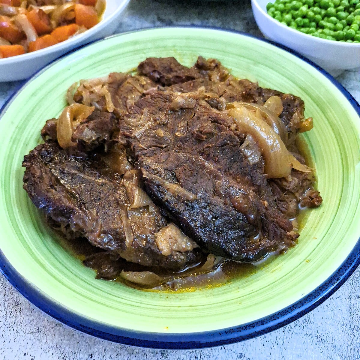 Slices of slow cooked beef transferred to a serving dish.