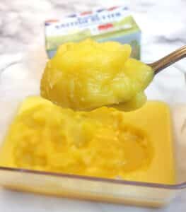 A spoonful of soft ghee being lifted from a dish.