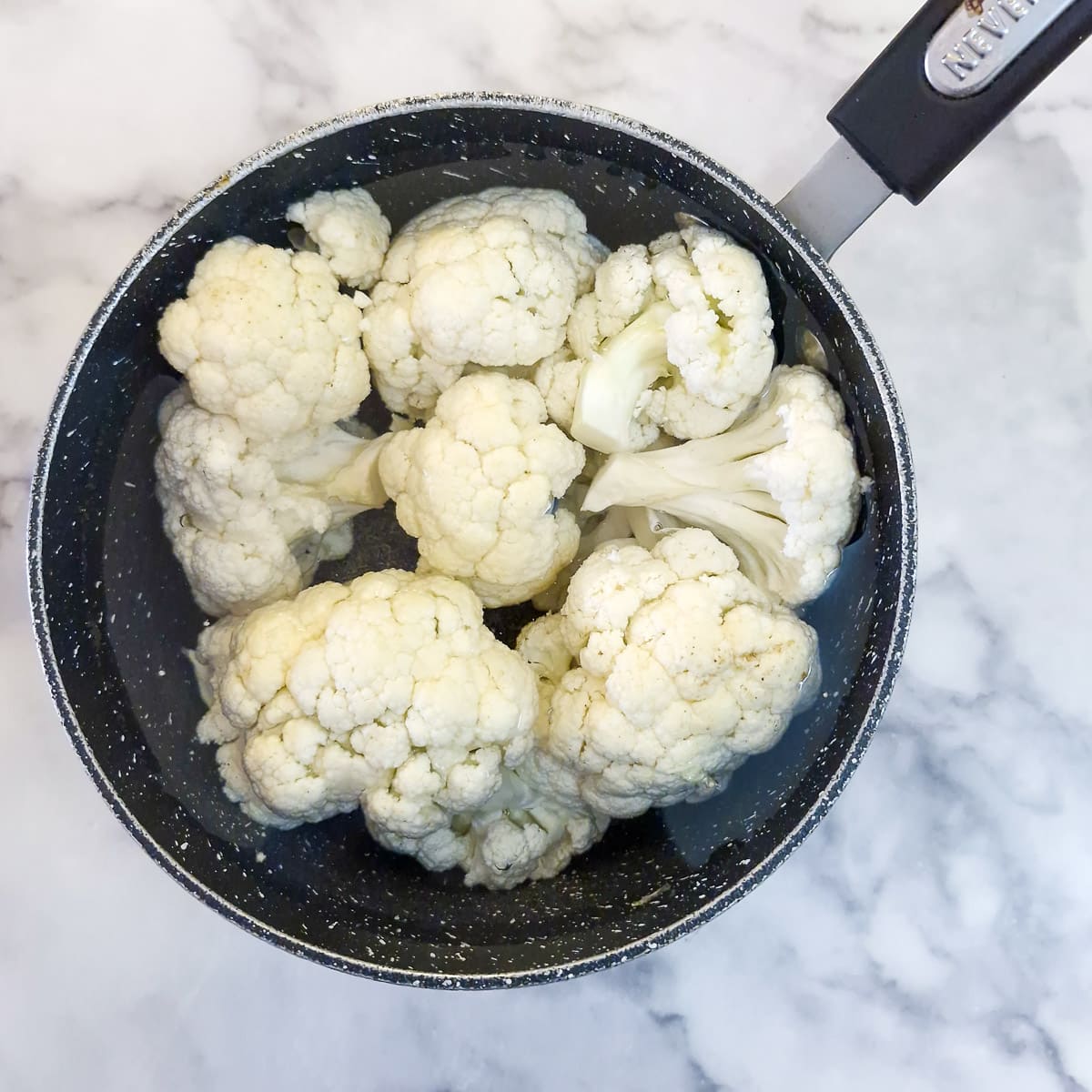 Step 1 - cauliflower florets boiling in a pan of water.