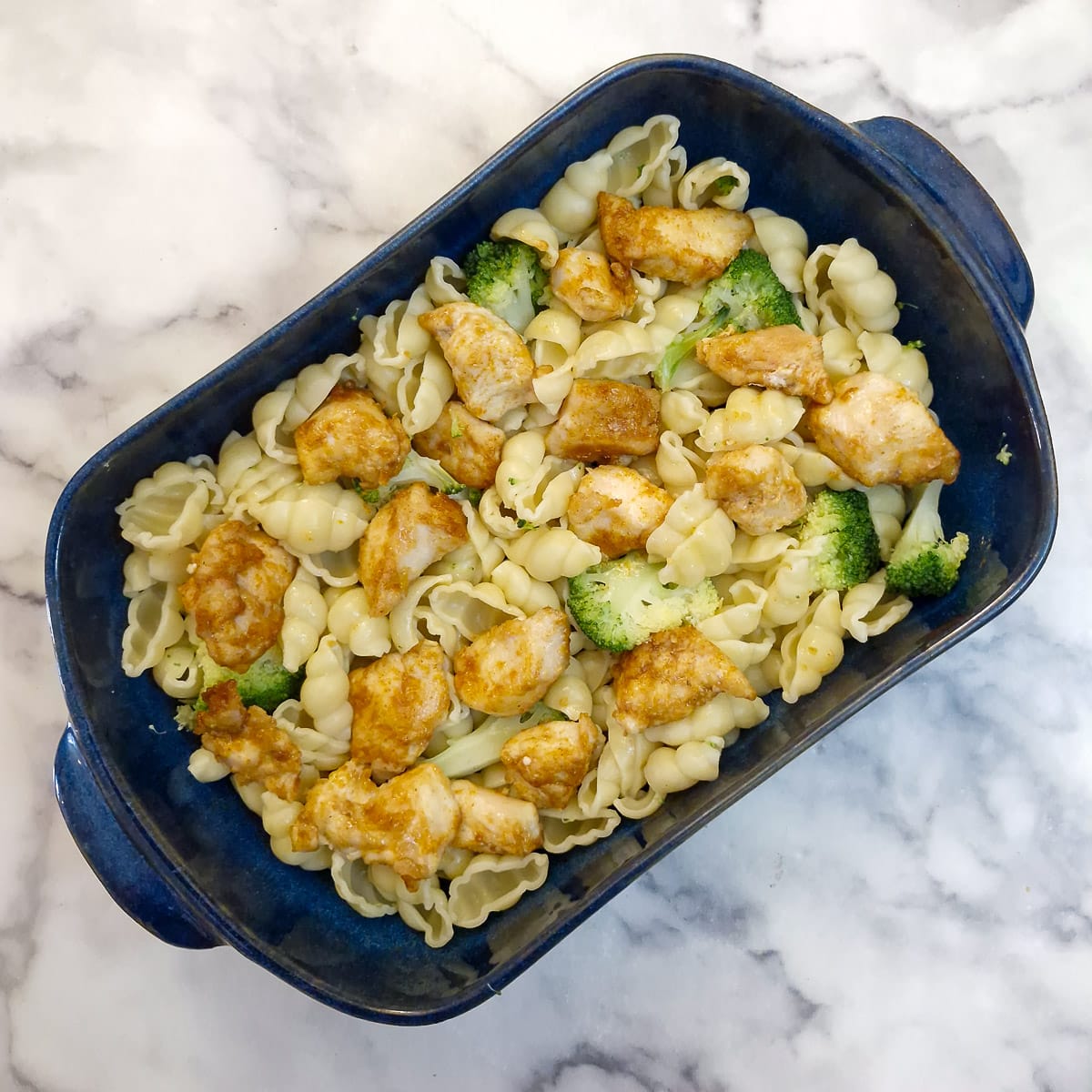 Step 3 - pasta, broccoli and chicken arranged in a casserole dish.
