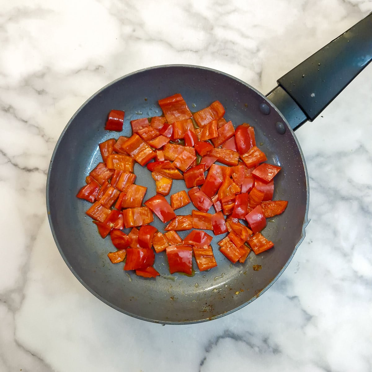 Step 4 - chopped red peppers softening in a frying pan.