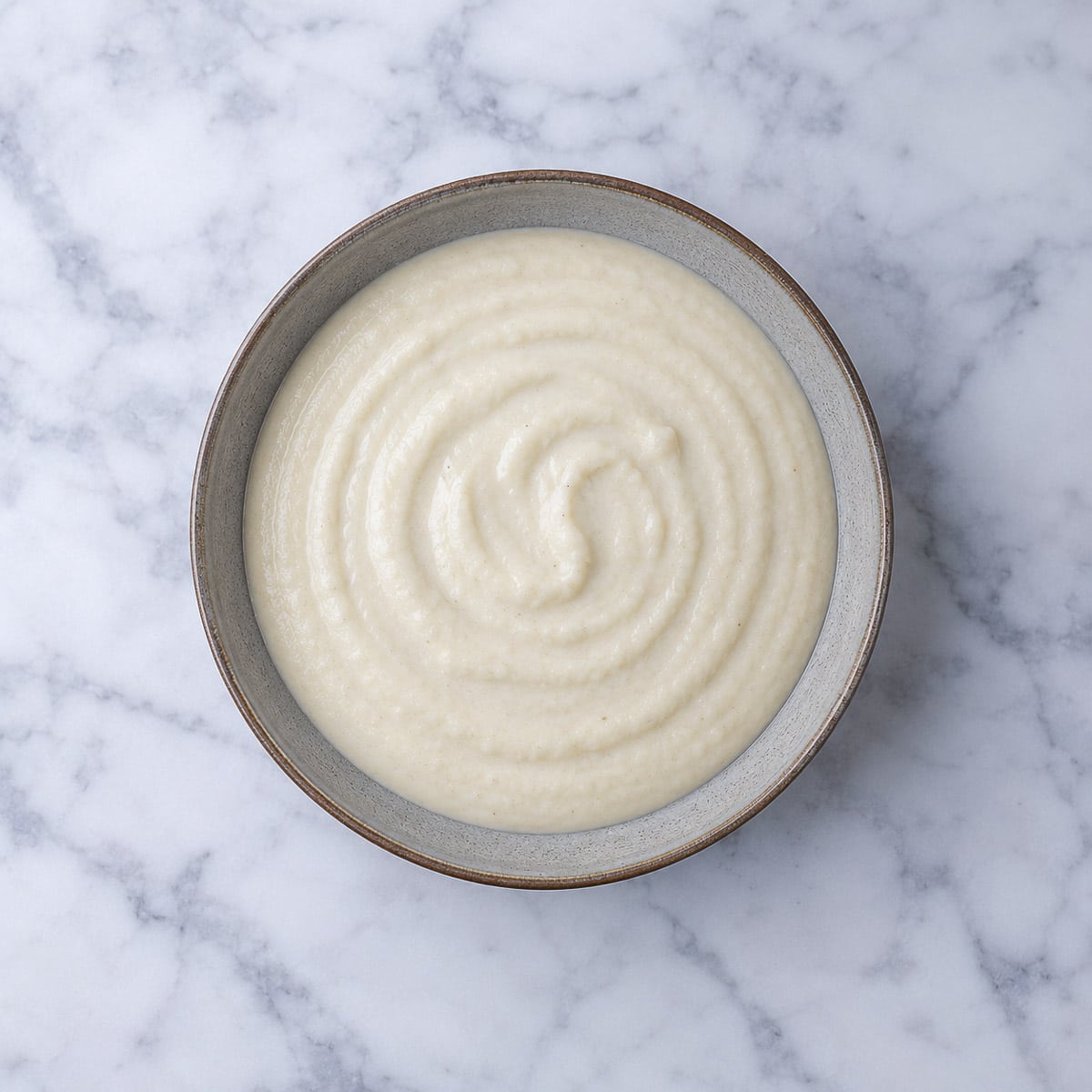 Overhead shot of parmesan cauliflower sauce in a grey bowl.