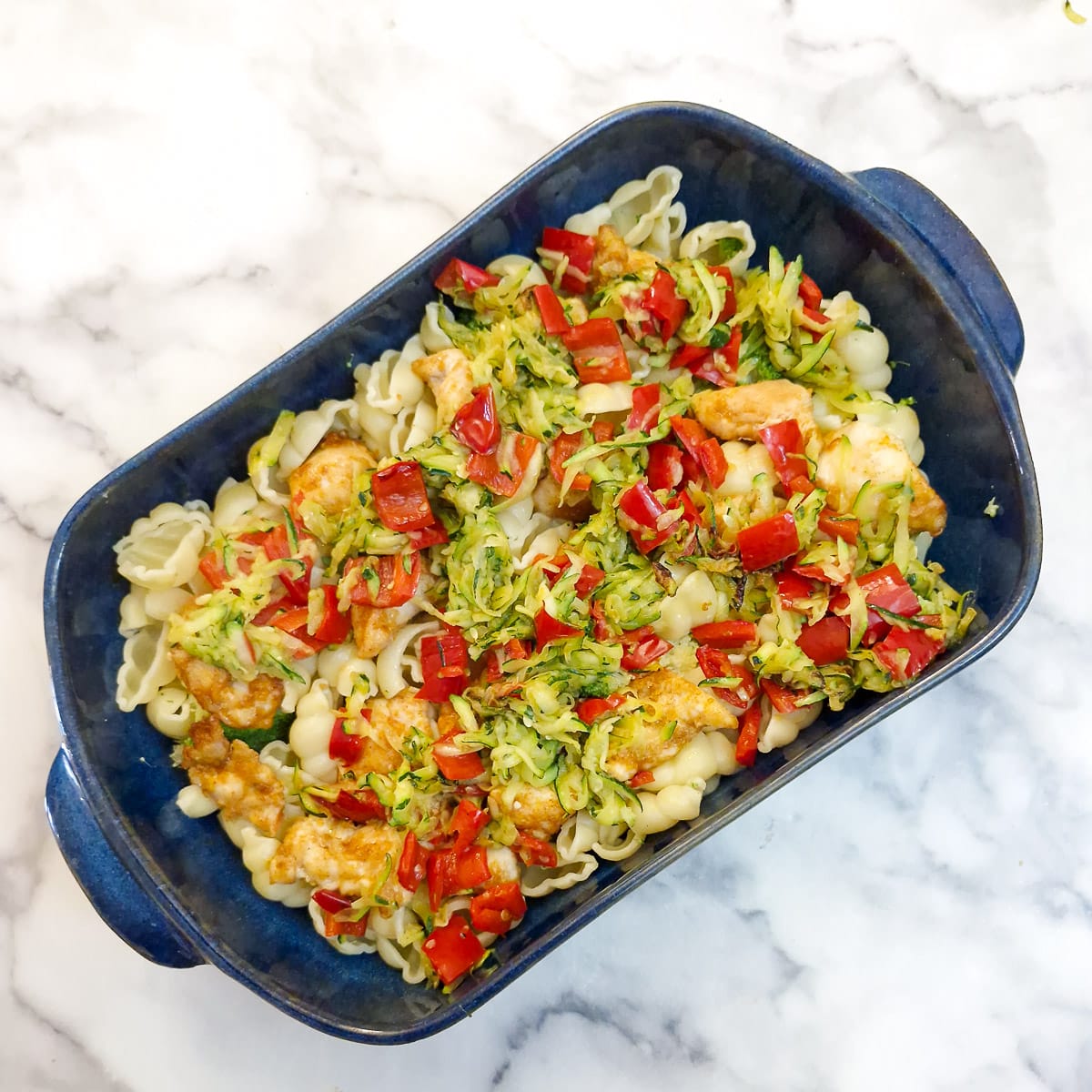 Step 6 - red peppers and courgettes added to the the chicken and pasta in the casserole dish.