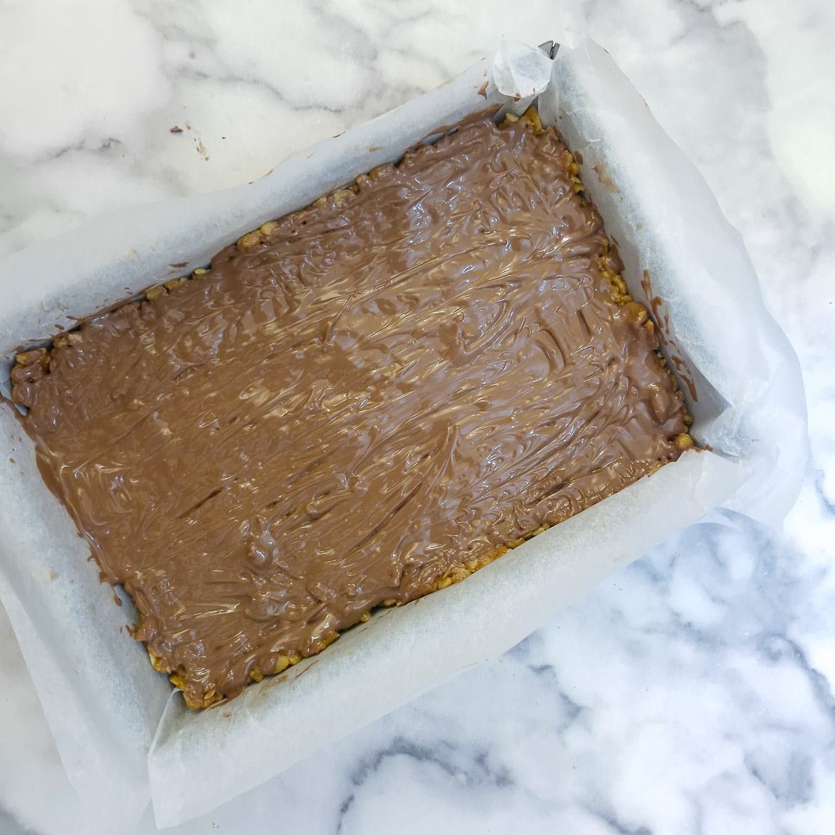 Step 7 - melted chocolate spread over the surface of the puffed rice slice.