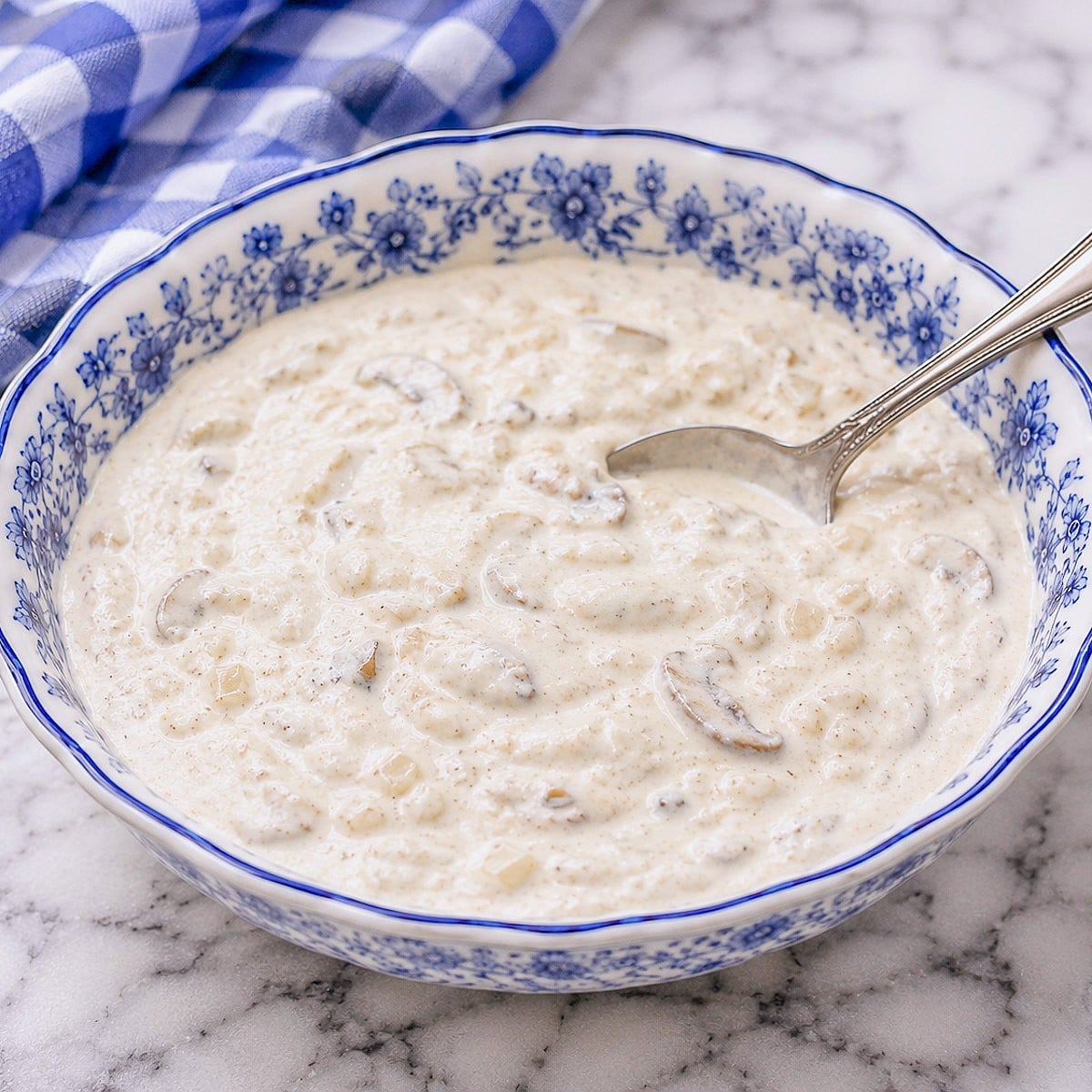 A blue-patterned dish filled with creamy mushroom and onion sauce.