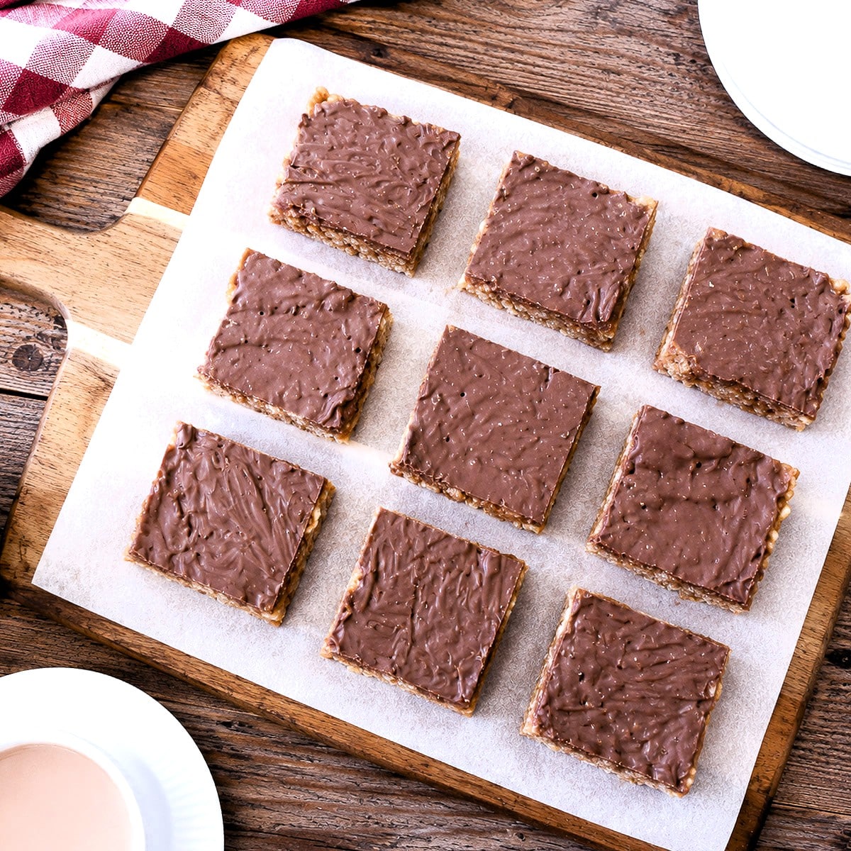 9 squares of Rice Krispie peanut bars on a wooden plank.