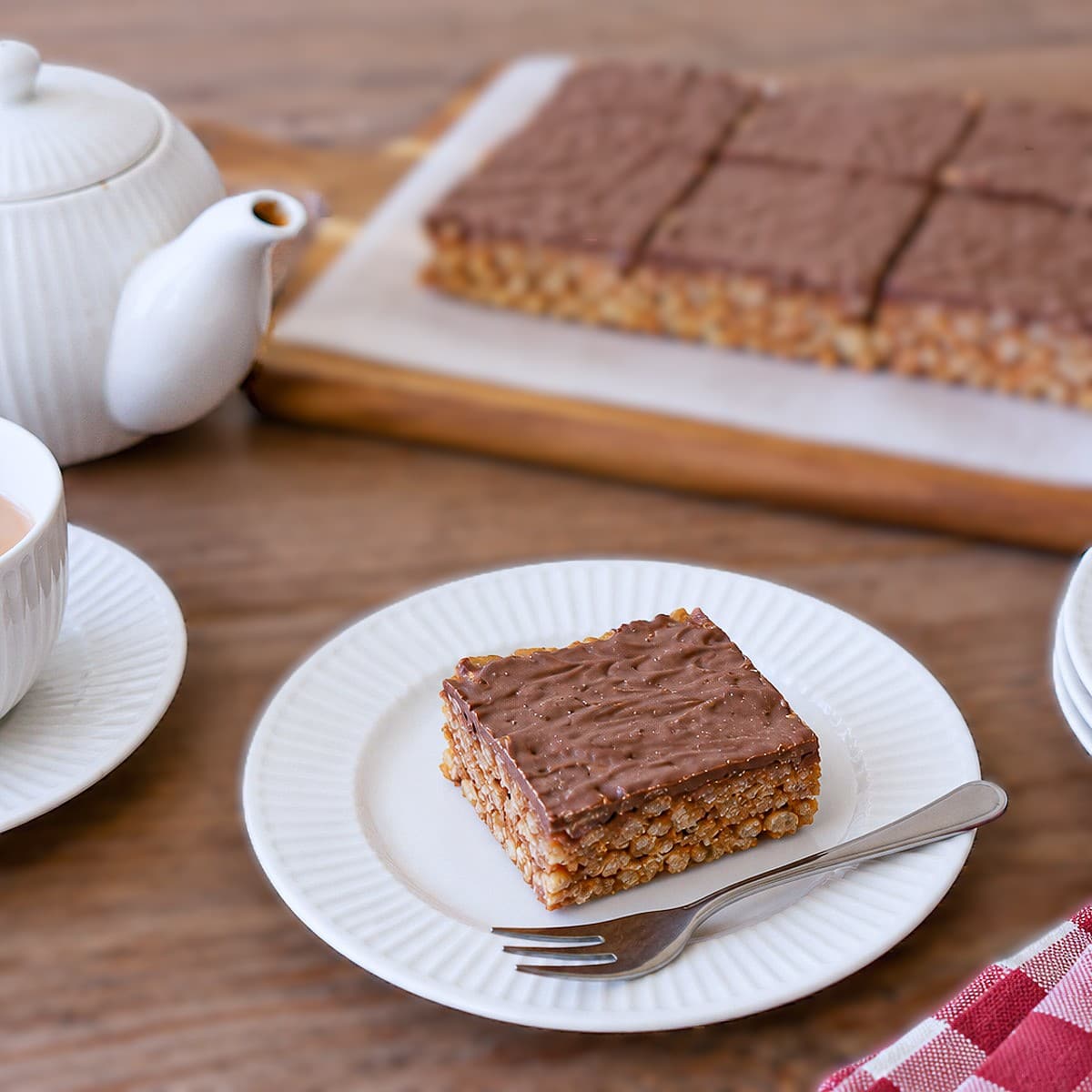 Cl;ose up of a square of peanut butter and chocolate cereal slice on a white plate with a cake fork.