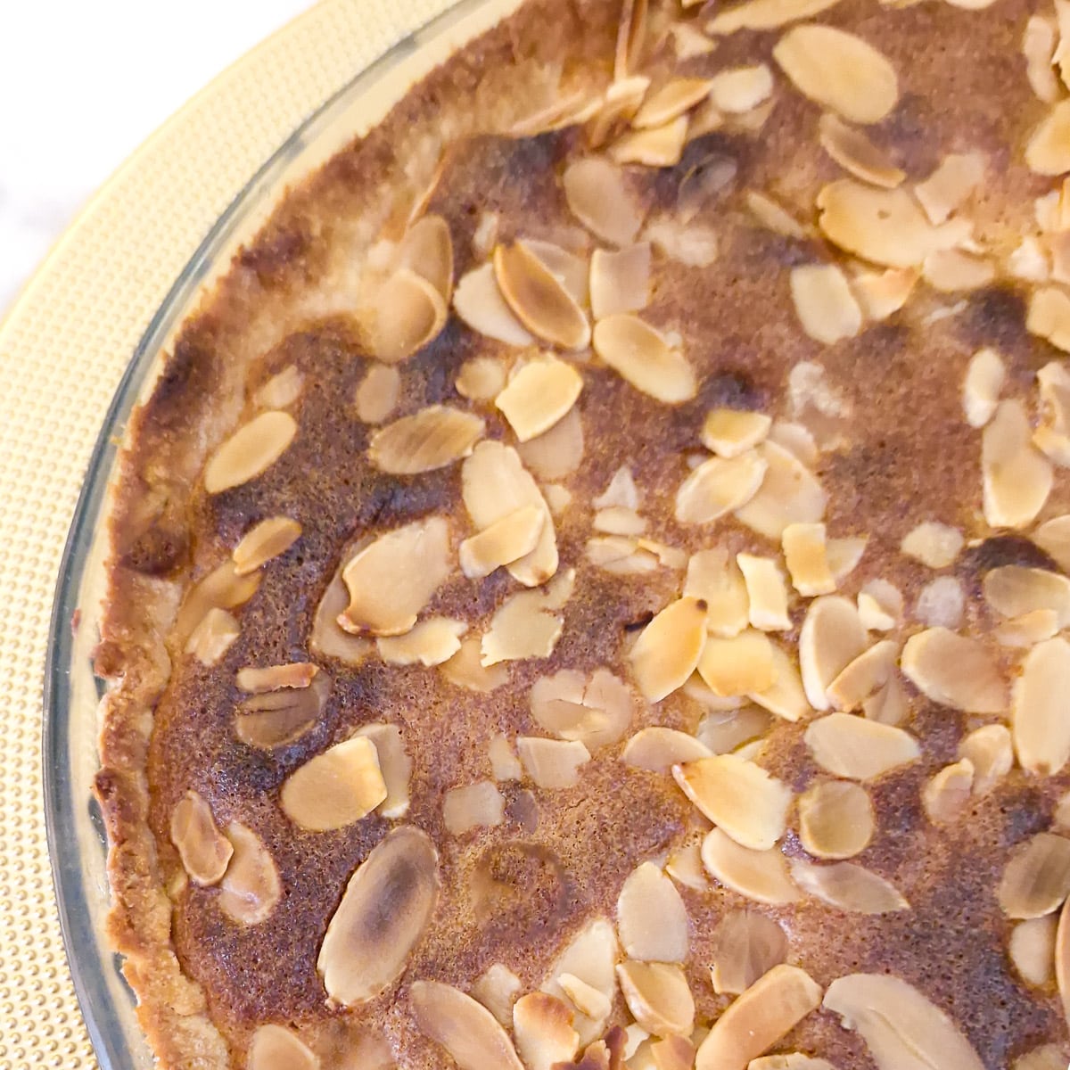 A closeup of the top of the frangipane tart, showikng the browned flaked almonds.