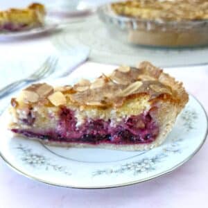 A slice of blackberry frangipane tart on a blue-patterned plate.