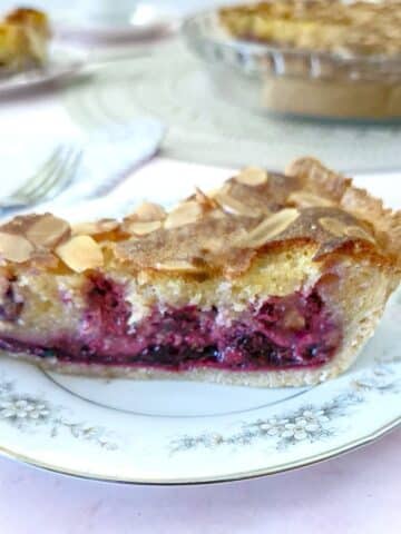 A slice of blackberry frangipane tart on a blue-patterned plate.