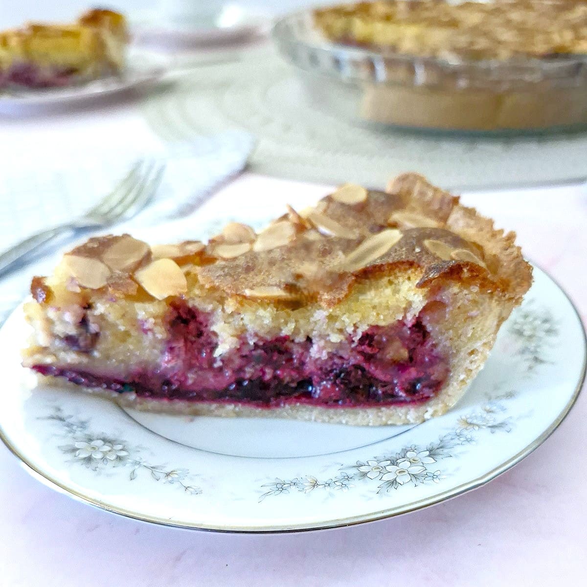 A slice of blackberry frangipane tart on a blue-patterned plate.