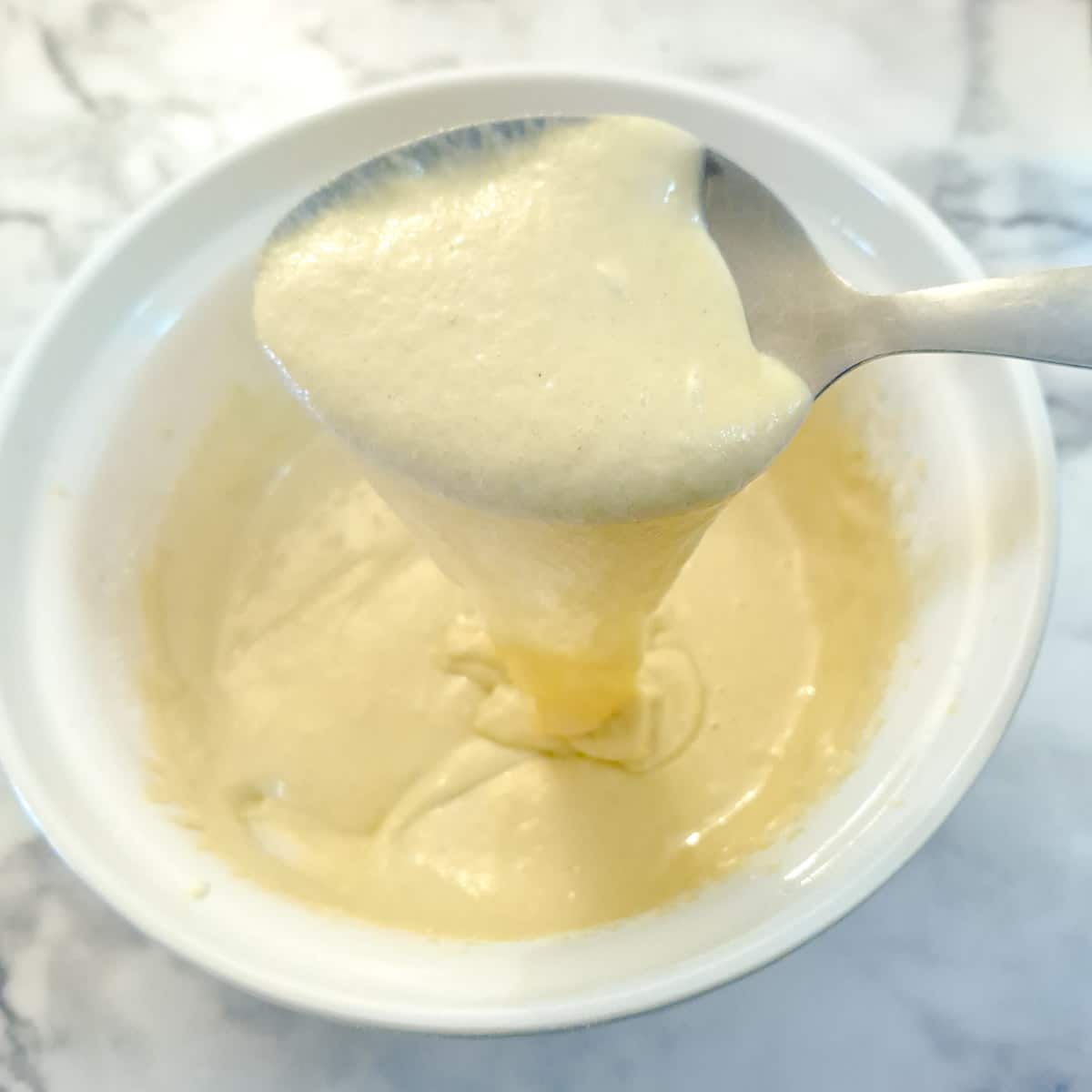 Step 3 - A spoonfl of batter being lifted from the mixing bowl to show the consistency.