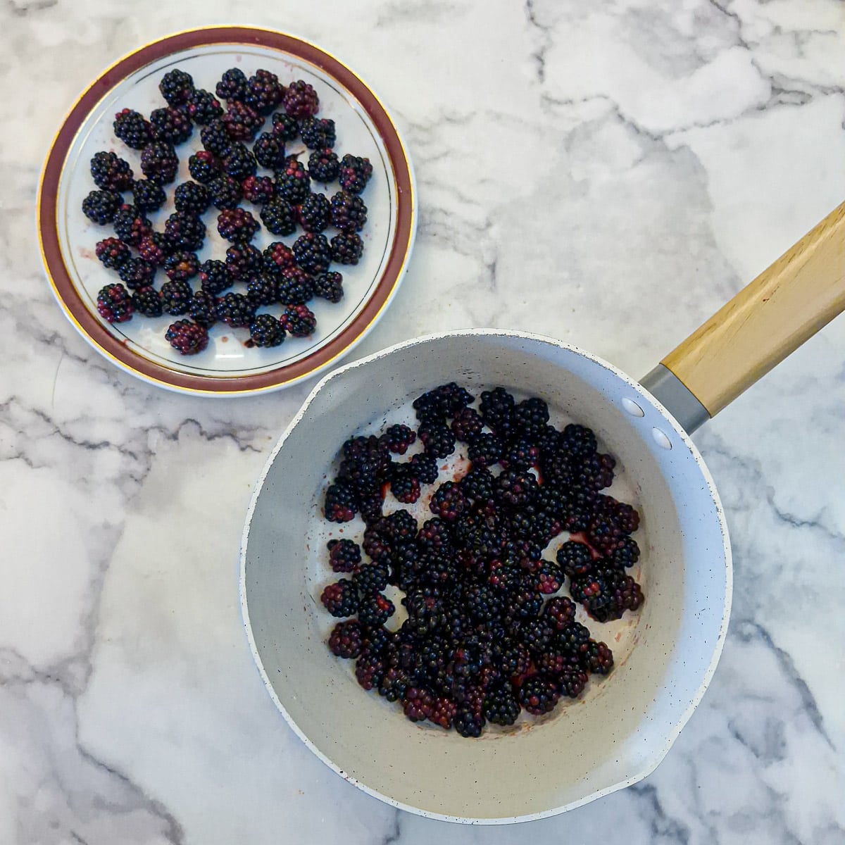 Step 4 - Blackberries in a saucepan with a few more whole blackberries on a plate.