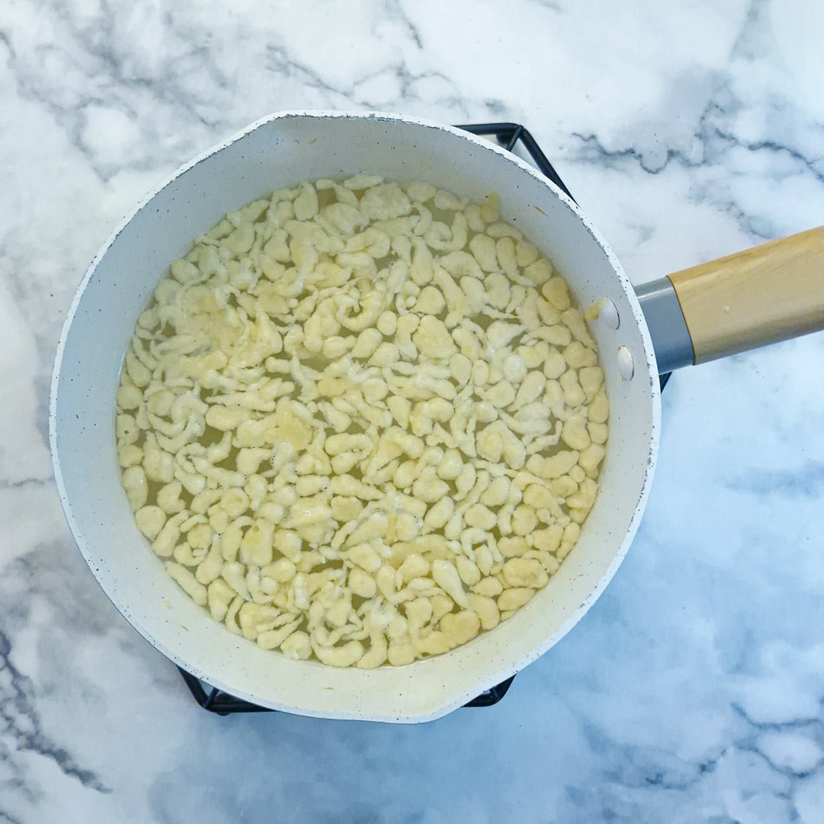 Step 5 - a pan of water with spaetzle floating on top.