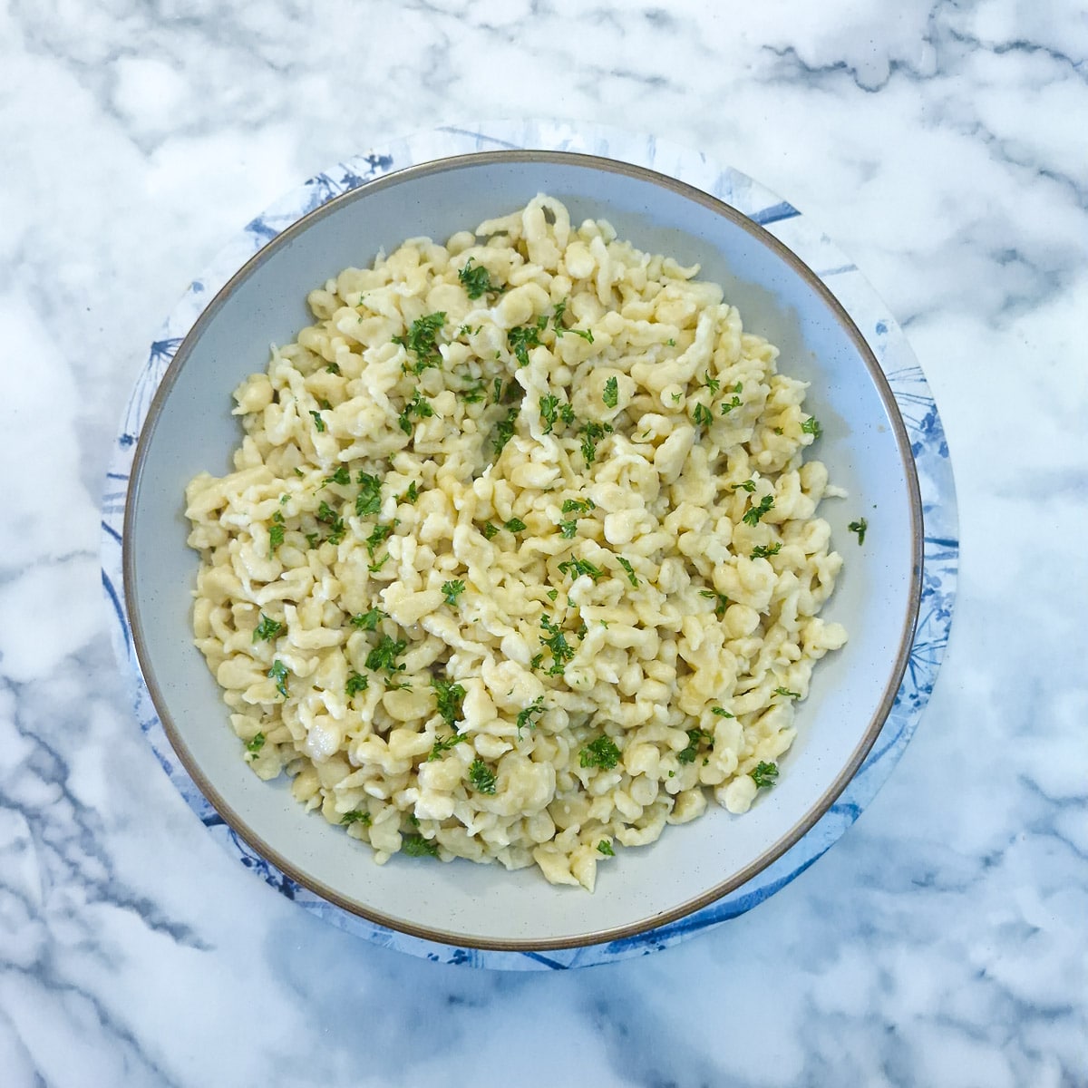 Step 6 - Spaetzle transferred to a serving dish and garnished with chopped parsley.