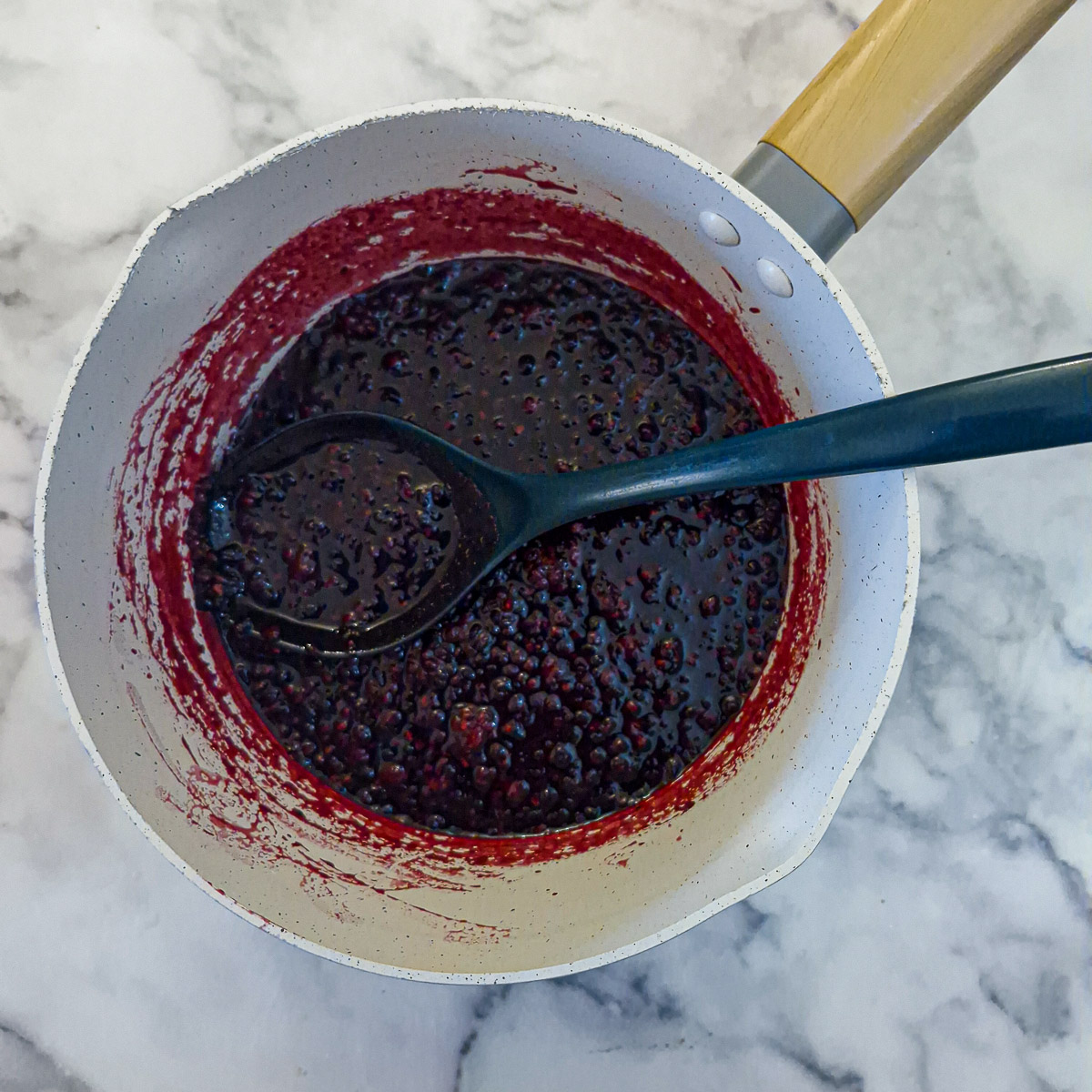 Step 6 - cooked blackberries that have formed a thick compote in a saucepan.