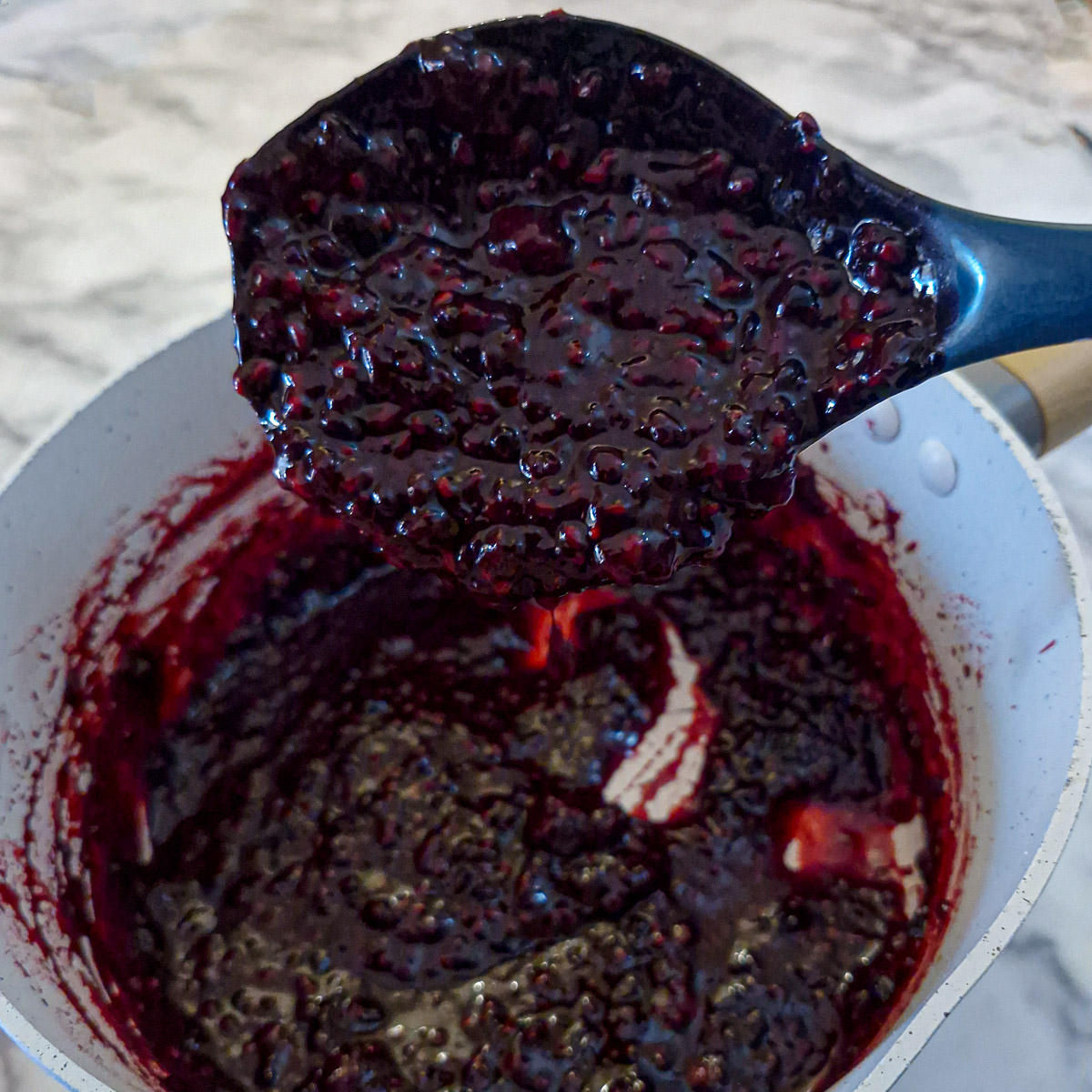 Step 7 - close of of blackberry compote on a spoon showing the thick consistency.