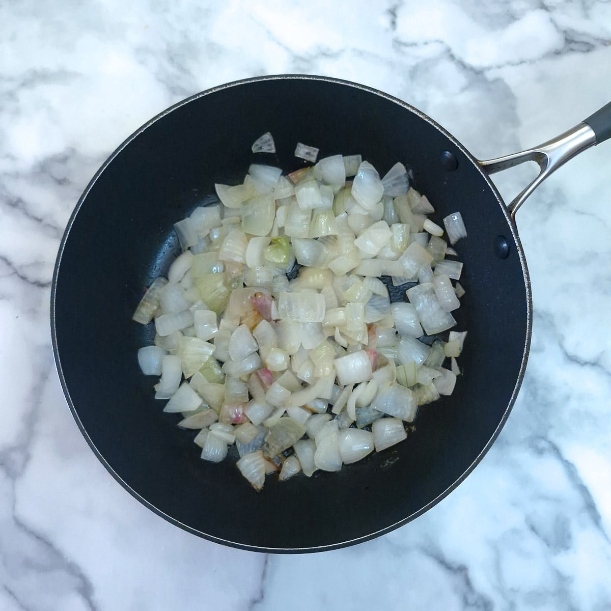 Step 1 - diced onions being sauteed in a pan.