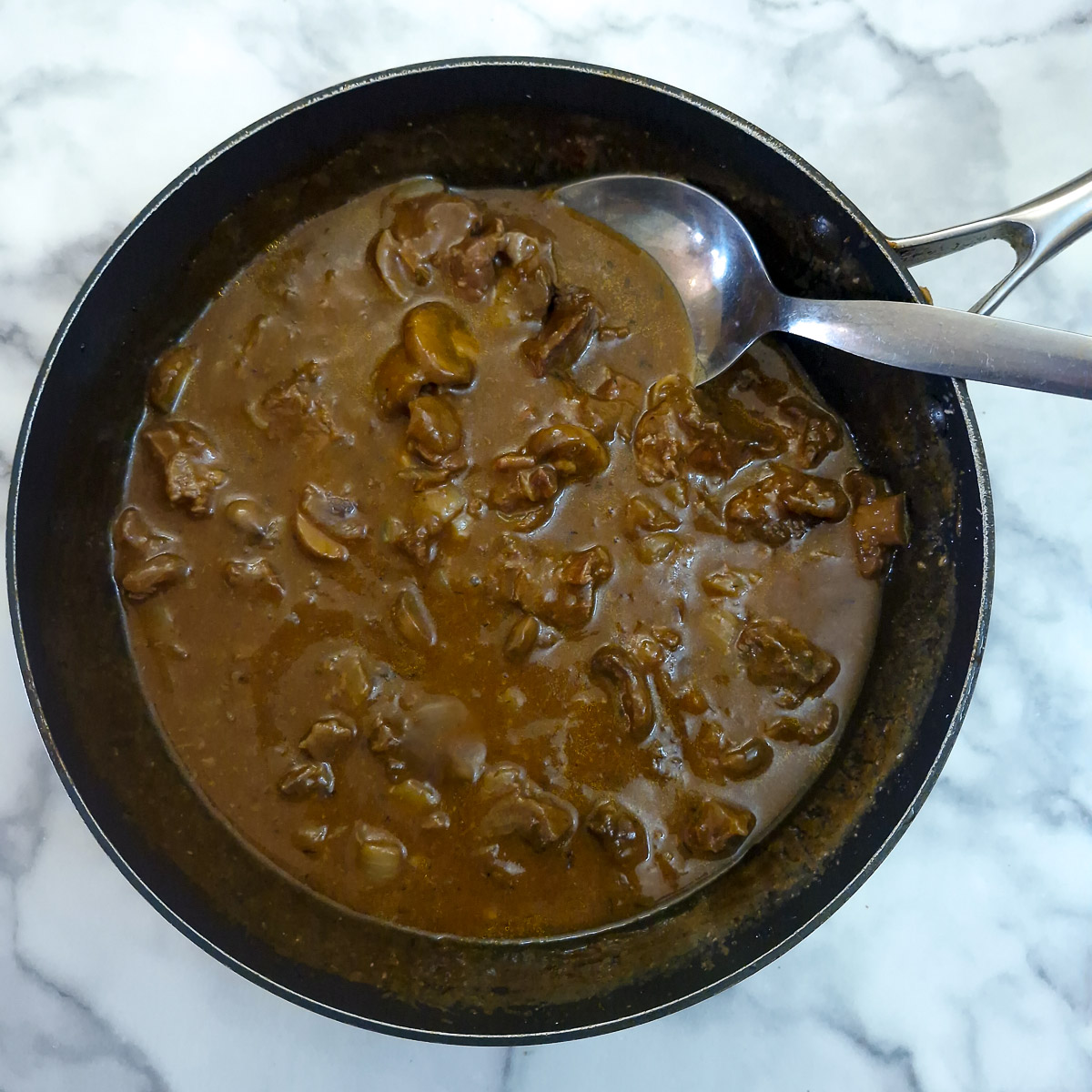 Step 6 - the cooked stew in a pan with a spoon.