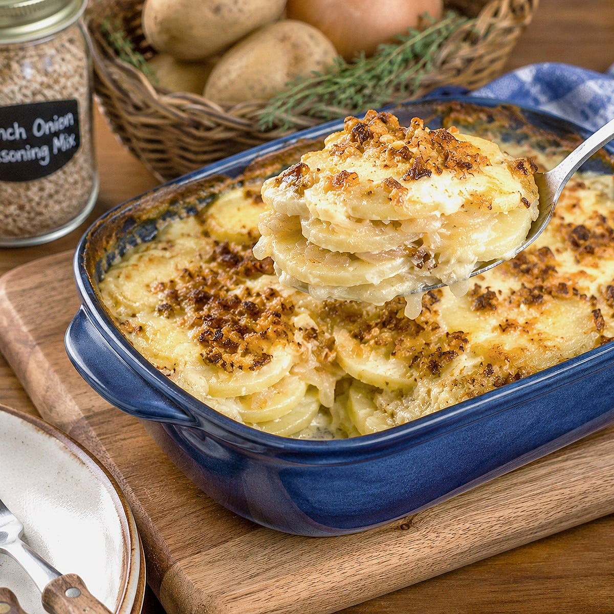 A spoonful of French onion potato bake being lifted brom the baking dish.