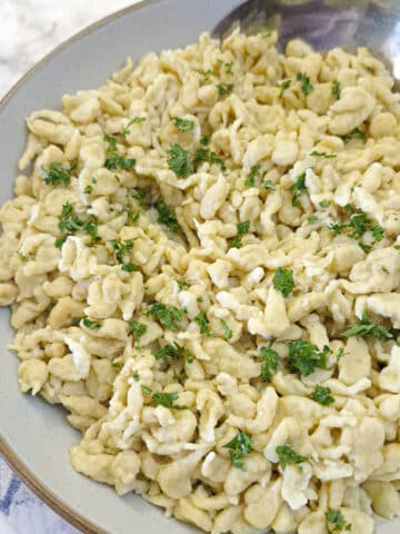 Closeup of a dish of spaetzle garnikshed with chopped parsley.