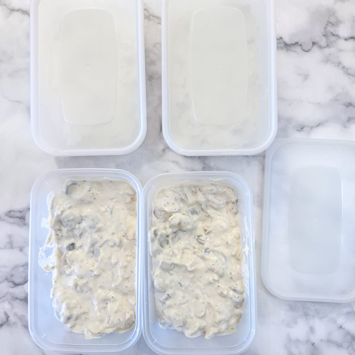 4 plastic freezer containers filled with creamy mushroom sauce.