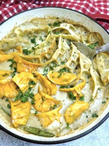 A red casserole dish filled with Thai green curry gyoza bake.