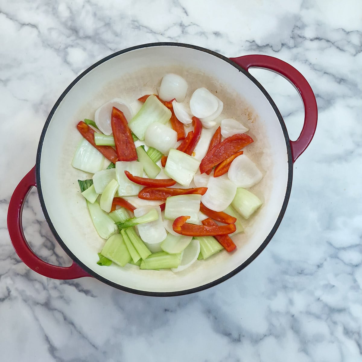 Step 1 - Red bell pepper, onion petals and pak choi stalks softening in a pan.