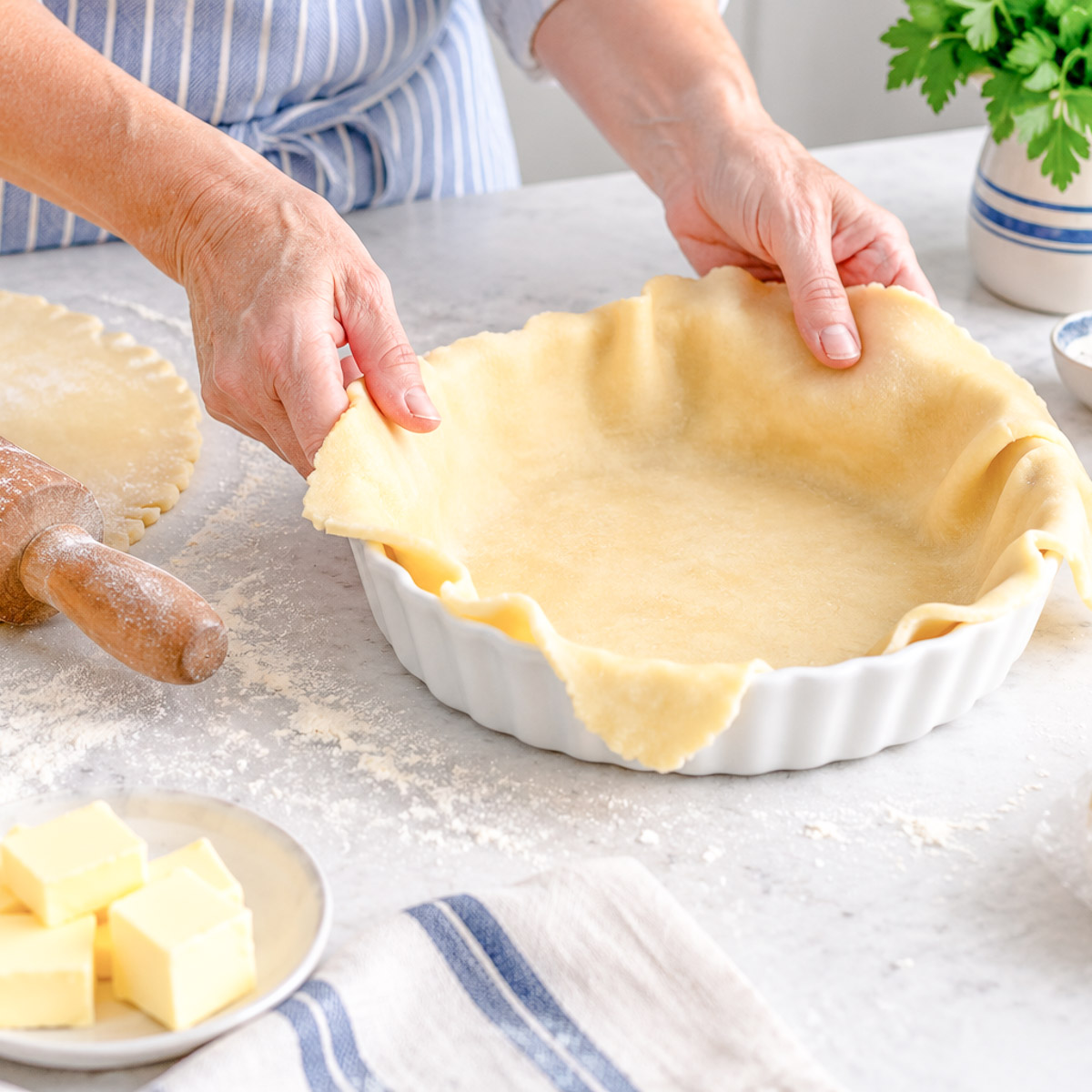 A pie dish being lined with shortcrust pastry.