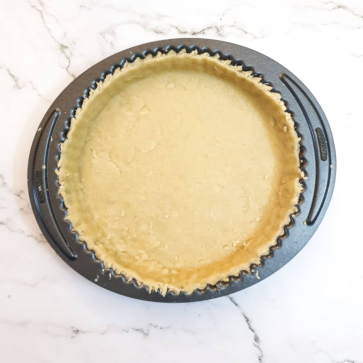 A flan dish lined with pastry.