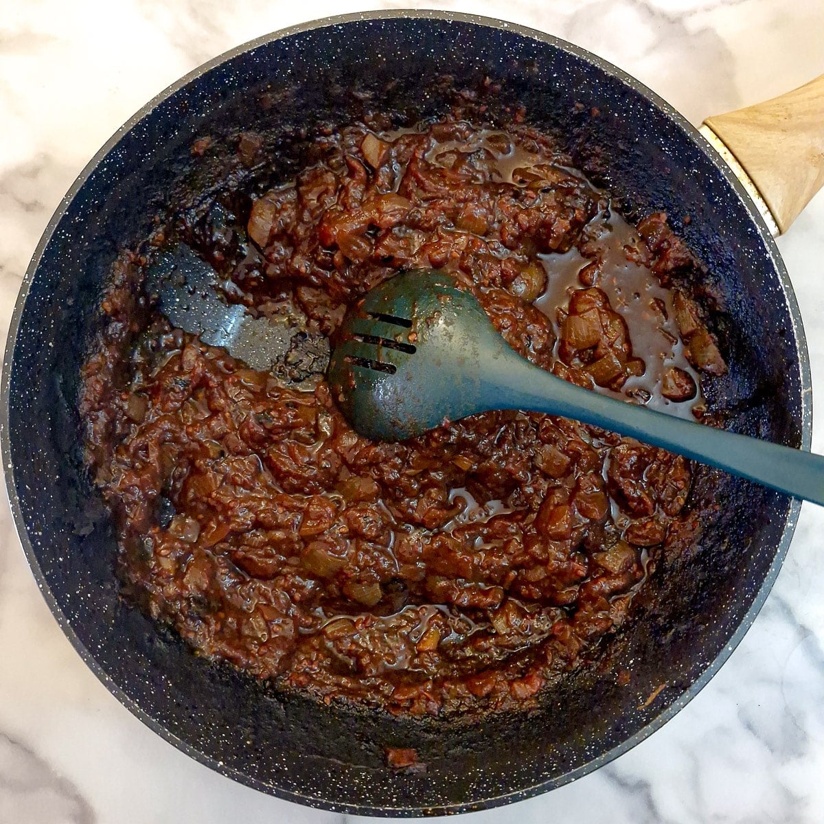 Step 4 - tomato chutney being tested for thickness by drawing a spoon through it.
